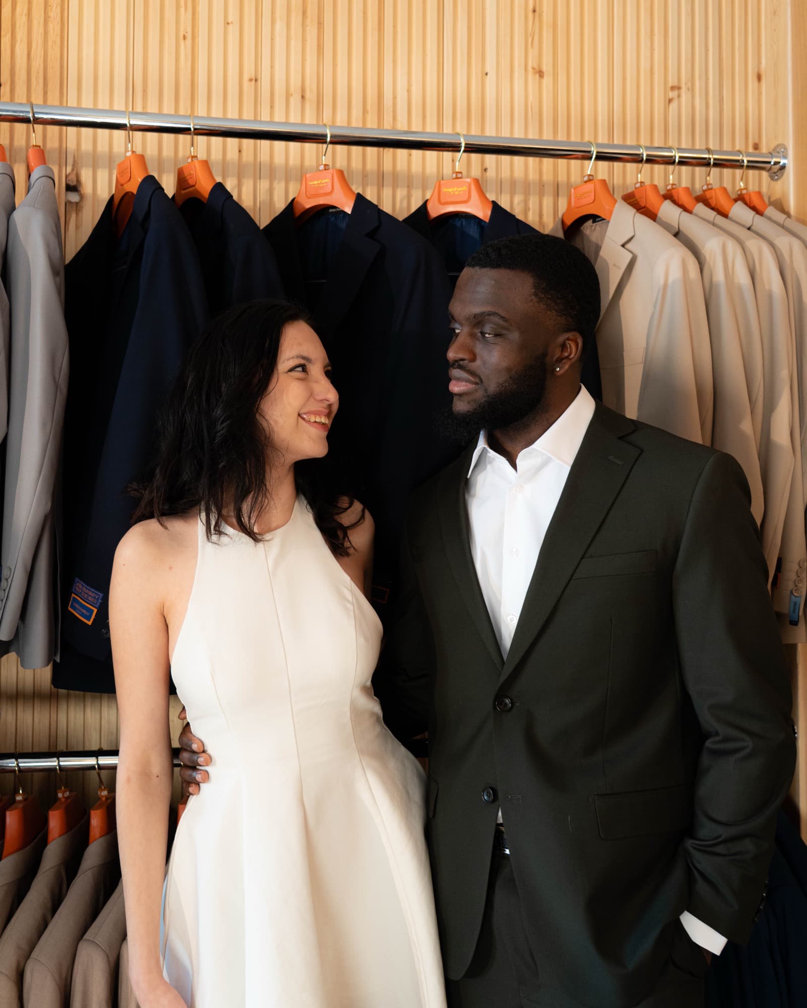 Couple looking at each other in front of the suit rack